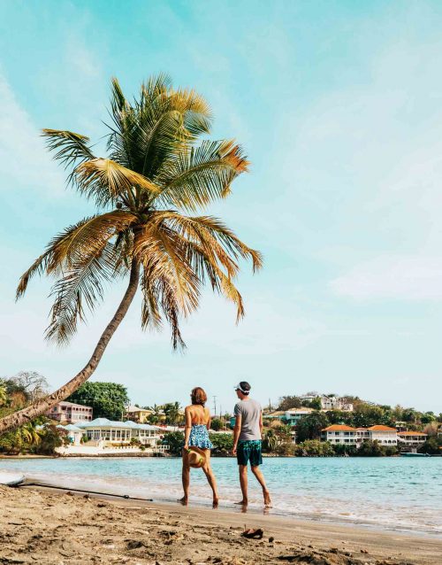 A couple walking down a beach in Grenada